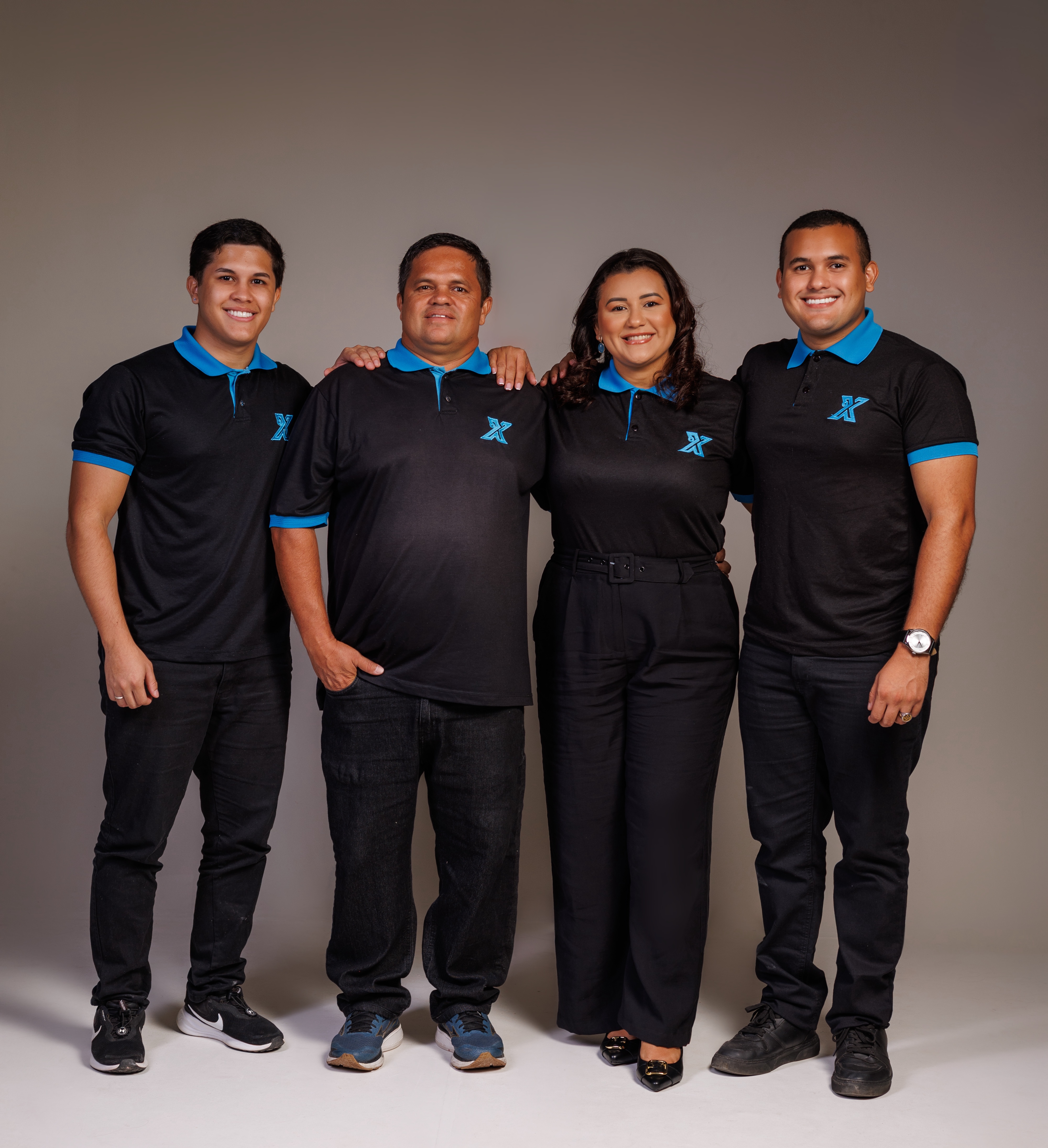 Os quatro fundadores da Extra Serviços: Alex Martins, Suziana Lima, Alex Silva e Luan Martins, em pé com a camiseta polo preta com o X azul da marca